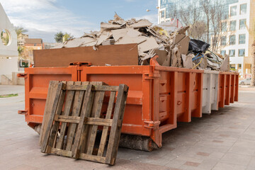 huge heap on metal big overloaded dumpster waste container filled with construction waste, drywall a