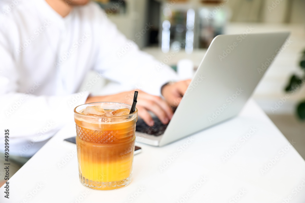 Glass of cocktail with ice on table in cafe, closeup