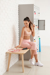 Sticker - Sporty young woman sitting on bench near locker in change-room