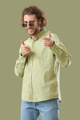 Wall Mural - Handsome man in sunglasses pointing at viewer on green background