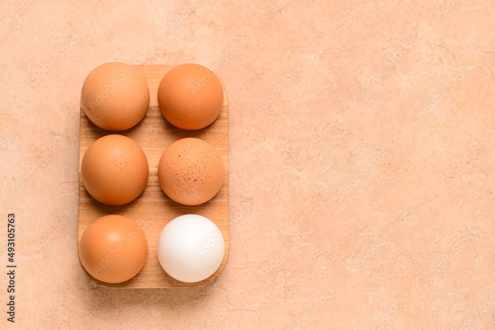 Holder with fresh chicken eggs on beige background