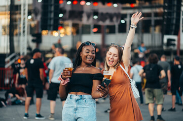 Friends using smartphone and drinking beer on a music festival