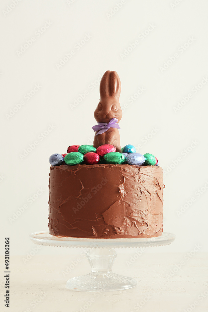 Tasty Easter cake decorated with chocolate bunny and eggs on light background