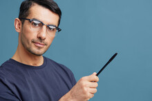 Man In Blue T-shirts With A Pen In Hand Posing Emotions Blue Background