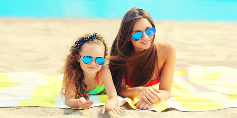 Wall Mural - Summer vacation portrait mother and child lying together on beach, background of sea