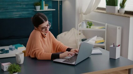 Wall Mural - Student talking on phone call and working on laptop at home, multitasking to learn educational information on online school lesson. Adult browsing internet and using smartphone for communication.