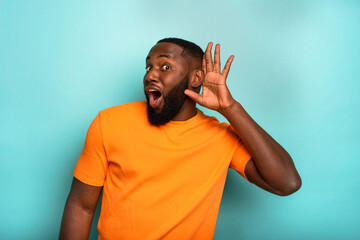 Wall Mural - man speaks in the ear to a friend about a great promotion. amazed expression. cyan background