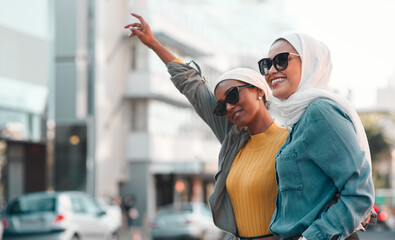 Poster - Taxi please. Cropped shot of two attractive young women wearing sunglasses and headscarves while hailing a taxi in the city.