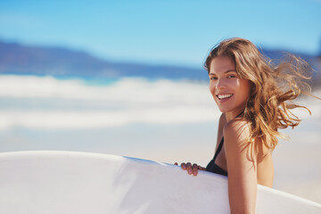 Wall Mural - Surfs up. Portrait of a young surfer standing on the beach.