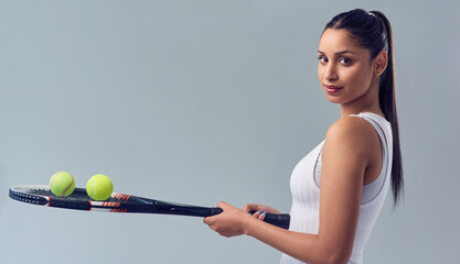 Think youve got what it takes. Cropped portrait of an attractive young female tennis player posing against a grey background in studio.