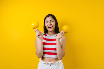 portrait of young latin woman holding mexican maracas or rattle on music concept and copy space on yellow background in Latin America	