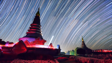 Wall Mural - star trails moving over a sacred temple at doi inthanon national park, chiang mai, thailand.