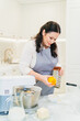 © andrey - a woman cook makes orange zest on a grater to make pastries or cream.