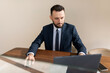 © Ivan Traimak - a man in a strict business suit works at the office walls behind a laptop