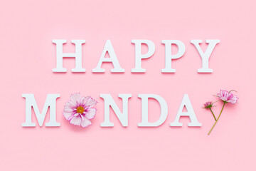 Happy Monday. Motivational quote from white letters and beauty natural flowers on pink background. Creative concept Hello Monday, positive mood