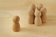 Wooden pawns representing group of people in circle and person alone - Concept of racism, social exclusion and isolation