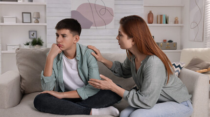 Mother consoling her depressed son at home. Teenager problems