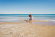 © nanihta - Wide view of a little girl wearing rainbow hoodie playing at the beach