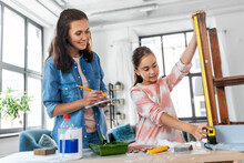 Family, Diy And Home Improvement Concept - Happy Smiling Mother And Daughter With Ruler Measuring Old Wooden Table For Renovation At Home