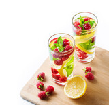Fototapeta Kuchnia - Detox fruits water with ice, raspberries, lemon, mint isolated on white background . Refreshing summer drinks, selective focus, above view