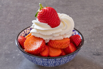 Canvas Print - bowl of strawberry with whipped cream close-up on a gray background