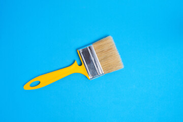 Bristly paint brush for painting and repair, on blue background.