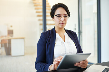 Poster - Fine-tuning some plans online. Cropped shot of a young businesswoman working on a digital tablet in a modern office.