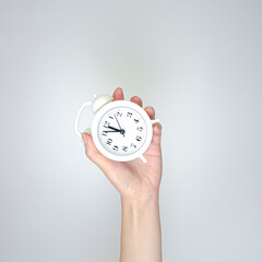 Hand holding alarm clock on light background. Schedule concept with empty copy space.