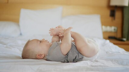 a nice little caucasian newborn baby is funny smiling, lying at the back in the child crib. portrait