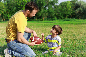 Sticker - Father teaching his little son how to play rugby on field