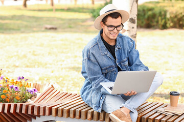 Sticker - Handsome man using laptop on bench in park