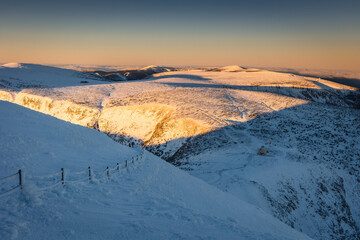 Winter view of the Meteorological Observatory on Śnieżka in the Karkonosze Mountains. The beautiful light of the rising sun creates an amazing atmosphere
