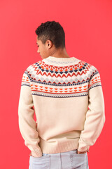 Wall Mural - Handsome African-American guy in knitted sweater on red background
