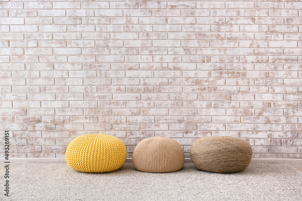 Modern poufs near light brick wall in room