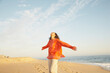 © Trinette Reed/Stocksy - Joyful woman with arms extended on beach on vacation
