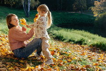 Woman And Child Playing With Dry Yellow Leaves