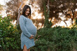 © Ezequiel Giménez/Stocksy - Smiling ethnic pregnant woman touching belly
