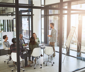 Wall Mural - Generating new ideas together. Shot of a businessman giving a presentation to his coworkers in a modern office.