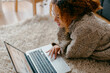 © Jimena Roquero/Stocksy - Girl working on laptop at home living room floor