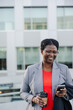 © Rob and Julia Campbell/Stocksy - Woman with phone near buildings in business suit.