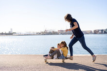 Mother And Children Riding Skateboard On Promenade