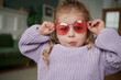 © Elena Kharichkina/Stocksy - Cute young girl with sunglasses making a surprised face.
