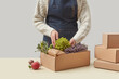 © Yaroslav Danylchenko/Stocksy - Woman in apron packing fresh vegetables in box