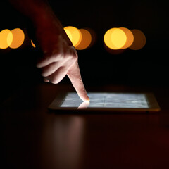 Poster - Putting in the late hours at work. Closeup shot of a persons finger using a digital tablet in the dark.