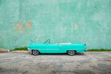 Old Aqua Colored Car Parked In Front Of A Wall
