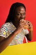 © Javier Díez/Stocksy - Happy woman eating burger in bright studio