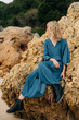 © Olga Moreira/Stocksy - Woman in vintage dress sitting on a rock