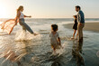 © Erin Brant/Stocksy - Joyful family playing in ocean tide at sunset