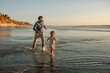 © Erin Brant/Stocksy - Dad running behind daughter in sea at sunset
