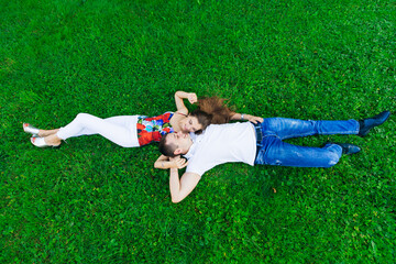 Romantic couple lying on the green grass lawn, hugging each other. drone view